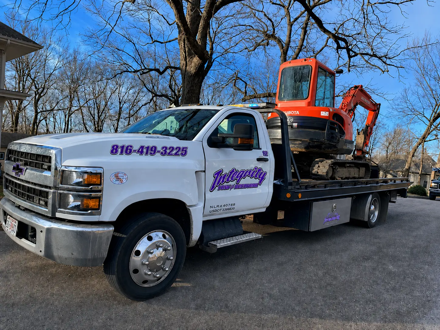 Integrity Tow & Recovery flatbed tow truck hauling a Kubota excavator